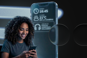 Mujer joven sonriendo mientras usa su smartphone, con una interfaz digital flotante que muestra datos contextuales como hora (16:45), clima (21°C) y un anuncio personalizado de audífonos. Estilo futurista de marketing contextual.