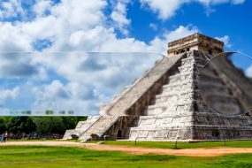 Pirámide de Kukulcán en Chichén Itzá bajo un cielo azul con nubes, con un efecto de desenfoque artístico en primer plano.