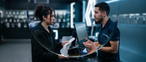 Clienta insatisfecha entrega un recibo a un empleado en el mostrador de una tienda, representando el momento post-venta que define la fidelización de clientes